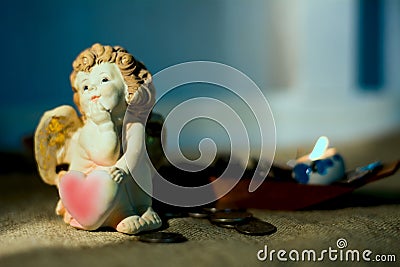 Figurine little angel with a heart who dreams of burning candles Stock Photo