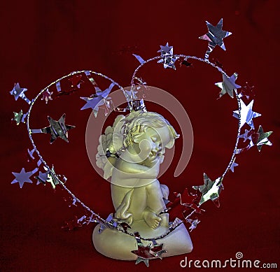 Figurine of a sleeping angel on a red background. Stock Photo