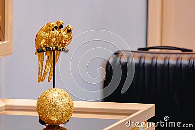 Figurine Three golden parrots on a perch in the interior of the room Stock Photo