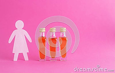 Figurine of a woman made of wood with bottles of alcohol on a pink background. Female alcoholism treatment concept, copy Stock Photo