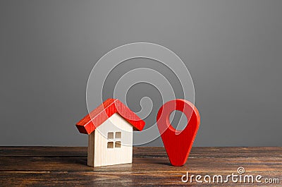 Figurine wooden house and red location pointer. Location and surroundings of the building. Moving in another home Stock Photo