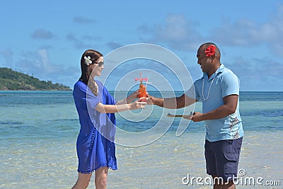 Fijian man serve a tropical cocktail drink to a tourist woman in Stock Photo