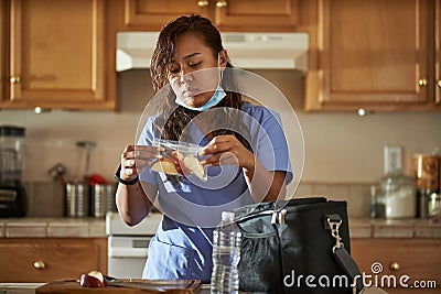 Filipina nurse in home kitchen packing lunch for work Stock Photo