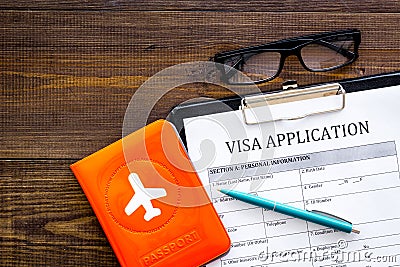 Fill visa application form. Empty blank near passport cover with airplane on dark wooden background top view copy space Stock Photo
