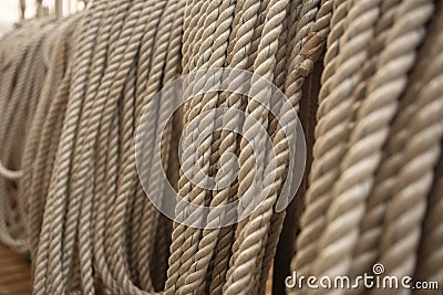 Filled frame background wallpaper photo of rows of beige plaited nautical tow ropes reeled together, hanging in lines on the deck Stock Photo