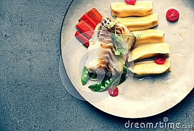 Fillet of cod with dumplings, carrots, green sweet pea and tomatoes at vegetarian restaurant Stock Photo