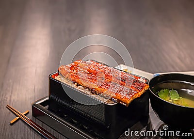 Fillets of japanese unagi eel grilled in a kabayaki style with a cup of misoshiru soup and chopsticks. Stock Photo