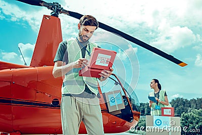 Attentive experienced bearded volunteer checking inside of first aid box Stock Photo