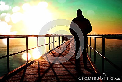 Film grain. Man silhouette walk on wharf construction above sea to Sun. Fantastic morning with clear sky, smooth water level Stock Photo
