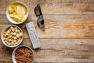 Film whatching party with glasses, crumbs, chips and pop corn wooden background top view mockup Stock Photo