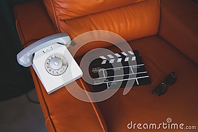 Filming some cinema movie..Vintage Brown leather armchair in loft design apartment..Old retro landline phone, sunglasses and Stock Photo