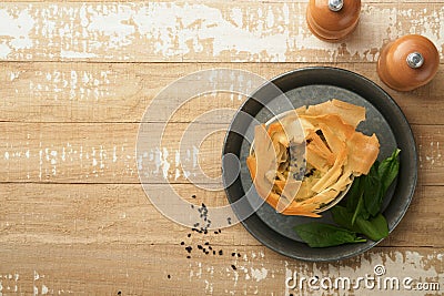 Filo pies with soft feta cheese and spinach in ceramic molds on old wooden table background. Filo portions pies. Small Baked Stock Photo