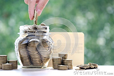 Finance, Woman hand putting a coin into glass bottle on nature green background,Business investment and Save money for prepare in Stock Photo