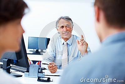 Financial advisor discussing plan with clients. Mature financial planner discussing plan with clients in office. Stock Photo