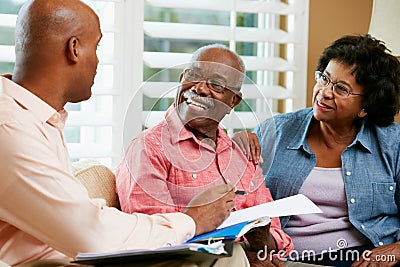 Financial Advisor Talking To Senior Couple At Home Stock Photo