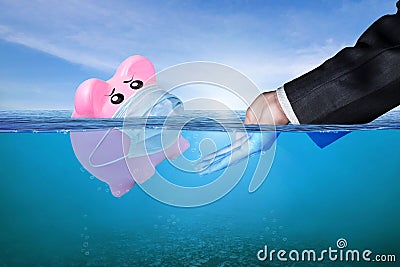 Financial Aid and rescue from debt problems for investments above water as a drowning pink piggy bank sinking in blue water Stock Photo