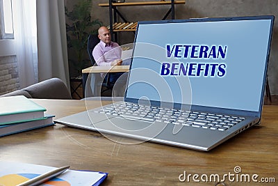 Financial concept meaning VETERAN BENEFITS with phrase on the Compact laptop A successful businessman with documents on the Stock Photo
