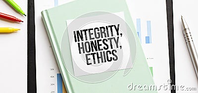 Financial diagram on white big notepad, green book and paper sheet with text INTEGRITY, HONESTY, ETHICS . Business concept Stock Photo