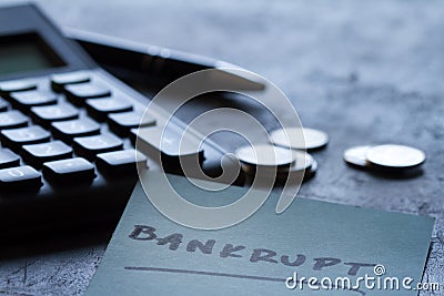 Financial failure, bankruptcy concept. Coins, calculator, pen and inscription bankrupt on dark background Stock Photo