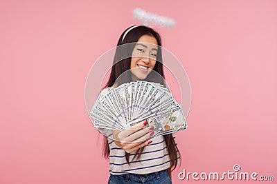 Financial wealth. Portrait of happy smiling girl with halo over head holding out money to camera Stock Photo