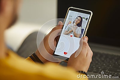 Single man looking at beautiful young woman`s profile photo on dating app and pressing like Stock Photo