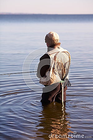 Finding calm in solitude. A fisherman waits in the water for a bite. Stock Photo