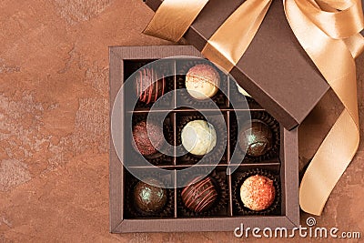 Fine chocolates in craft box with satin ribbon on a dark background. Flat layout. Festive concept. Copy space. Stock Photo