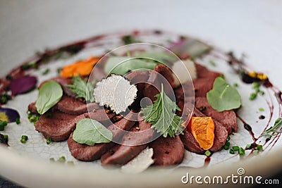 Fine Dining Meal on Plate in Restaurant. Beef Carpaccio with Black Truffles and Herbs. Closeup Stock Photo