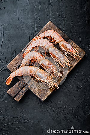 Fine selection of tiger prawns on cutting board on black textured background, top view Stock Photo