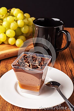 Finest chocolate dessert with chocolate chunks in focus, black cup with tea and fresh green grapes out of focus, Black background Stock Photo