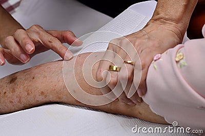The finger is locating the vein on the arm. Stock Photo