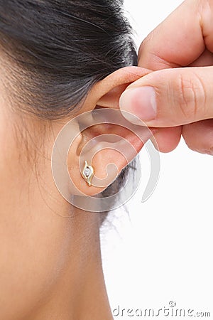 Finger pinching woman's ear Stock Photo
