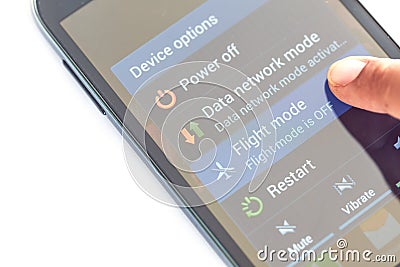 Finger press flight mode button on smartphone Stock Photo