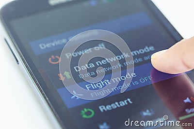 Finger press flight mode button on smartphone Stock Photo