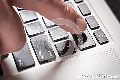 Finger is pressing delete key of computer keyboard, close up, top view Stock Photo