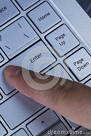 Finger pressing an enter key. Computer user hitting the enter key, up close. Confirmation, sending a message. Stock Photo
