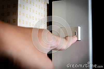 Finger switching the light at lighting switch Stock Photo