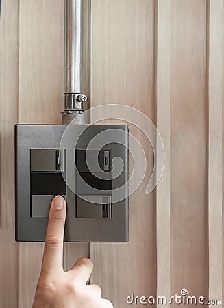 A finger is turning on a grey or black metallic light switch Stock Photo
