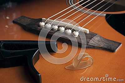 Fingerpick guitar concept: a thumb pick and a guitar capo laying on acoustic guitar Stock Photo