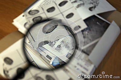 Fingerprint card on table, view through magnifying glass. Detective work Stock Photo