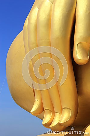 Fingers of biggest golden buddha statue on blue sky background Stock Photo