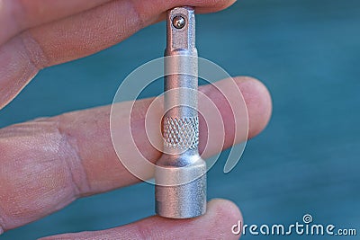 Fingers on the hand hold one small gray metal adapter for a screwdriver Stock Photo