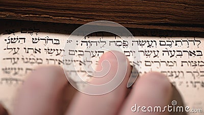 Fingers on page of old book Torah. Selective focus on snippet Hebrew Bible text: offer the Passover sacrifice to Jehovah Stock Photo