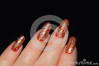 Fingers with red nail polish with silver and gold tinsel Stock Photo