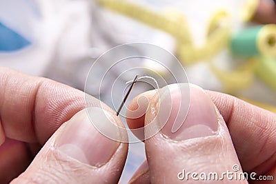 Fingers of a tailor threading a needle Stock Photo