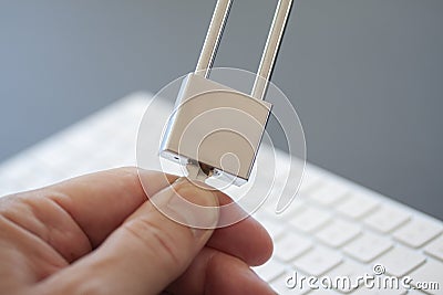 Fingers turning a key on stainless padlock in front of computer keyboard. PC network security, data security and antivirus protect Stock Photo