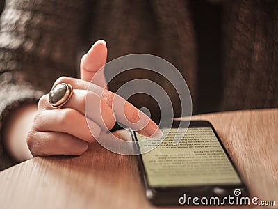 Fingers of a young white caucasian woman browsing a smartphone with 3G internet displaying a wide screen full of text Stock Photo