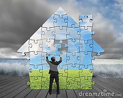 Finishing house shape puzzles assembling on pier with flood Stock Photo