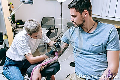 Blond short-haired tattoo artist working with remarkable tattoo Stock Photo