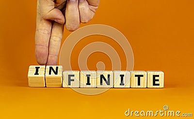 Finite or infinite symbol. Businessman turns wooden cubes and changes the word `finite` to `infinite`. Beautiful orange table, Stock Photo